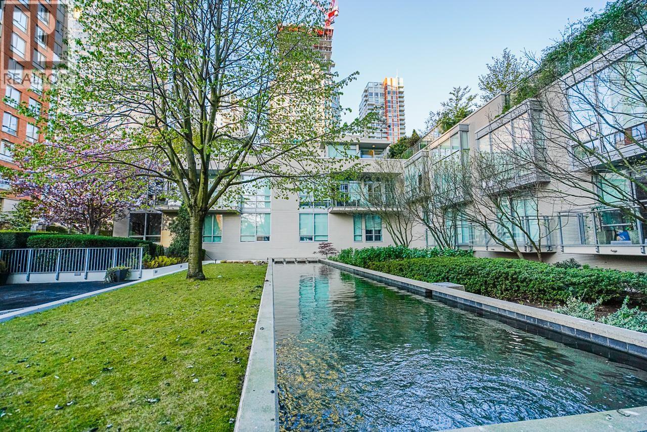 A small pool in a grassy area in front of a building.