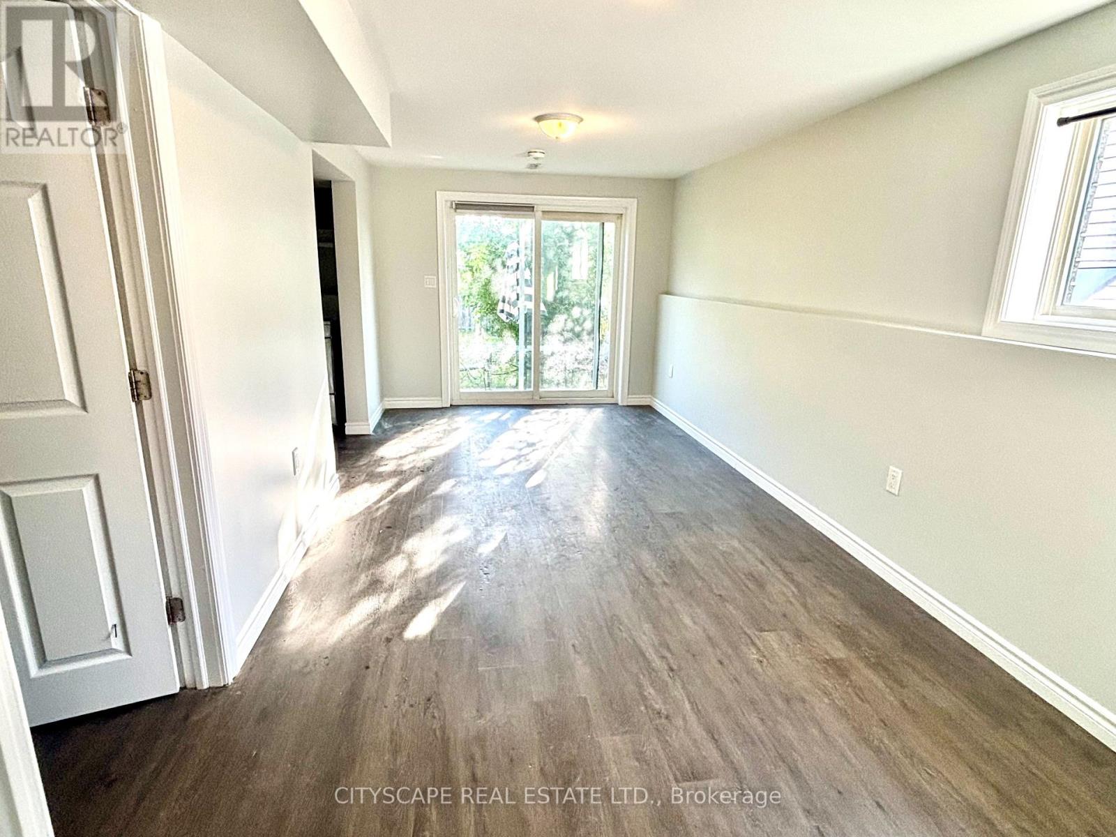 A room with wooden flooring and a sliding glass door leading outside.