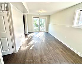 A room with wooden flooring and a sliding glass door leading outside.