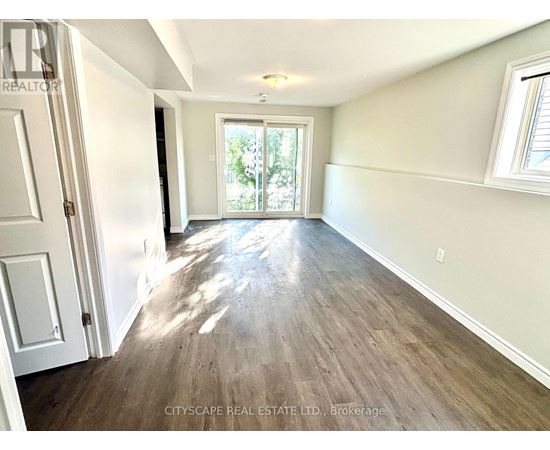 A room with wooden flooring and a sliding glass door leading outside.