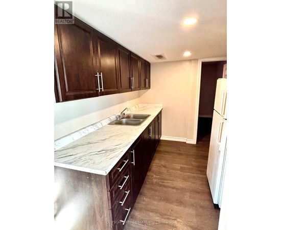 A kitchen with dark wood cabinets and a marble countertop.