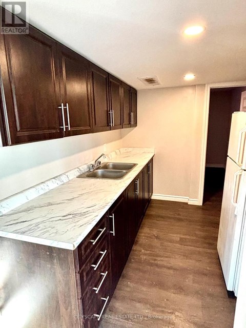 A kitchen with dark wood cabinets and a marble countertop.