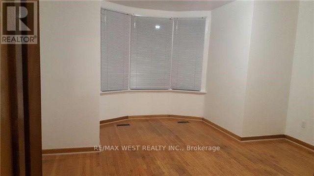 A room with a window covered by white blinds and wooden flooring.
