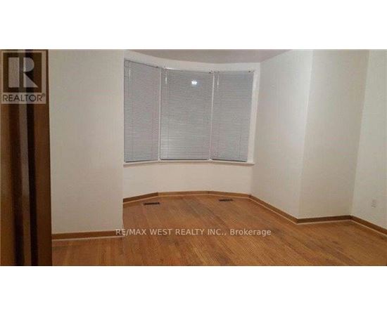 A room with a window covered by white blinds and wooden flooring.
