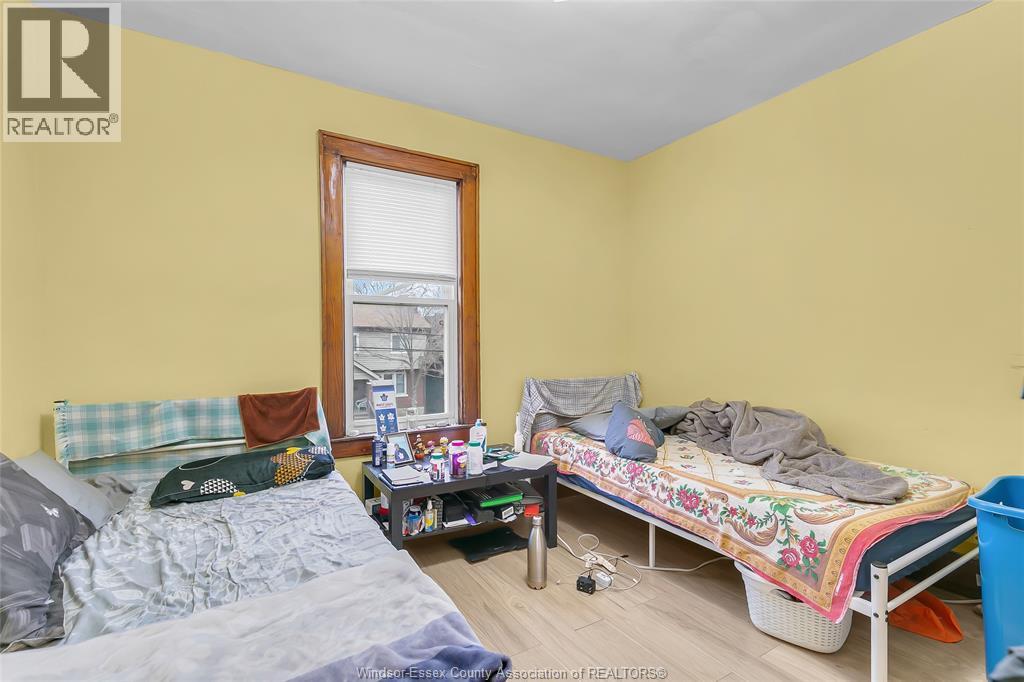A bedroom with a bed, a sofa, a window, and a nightstand.