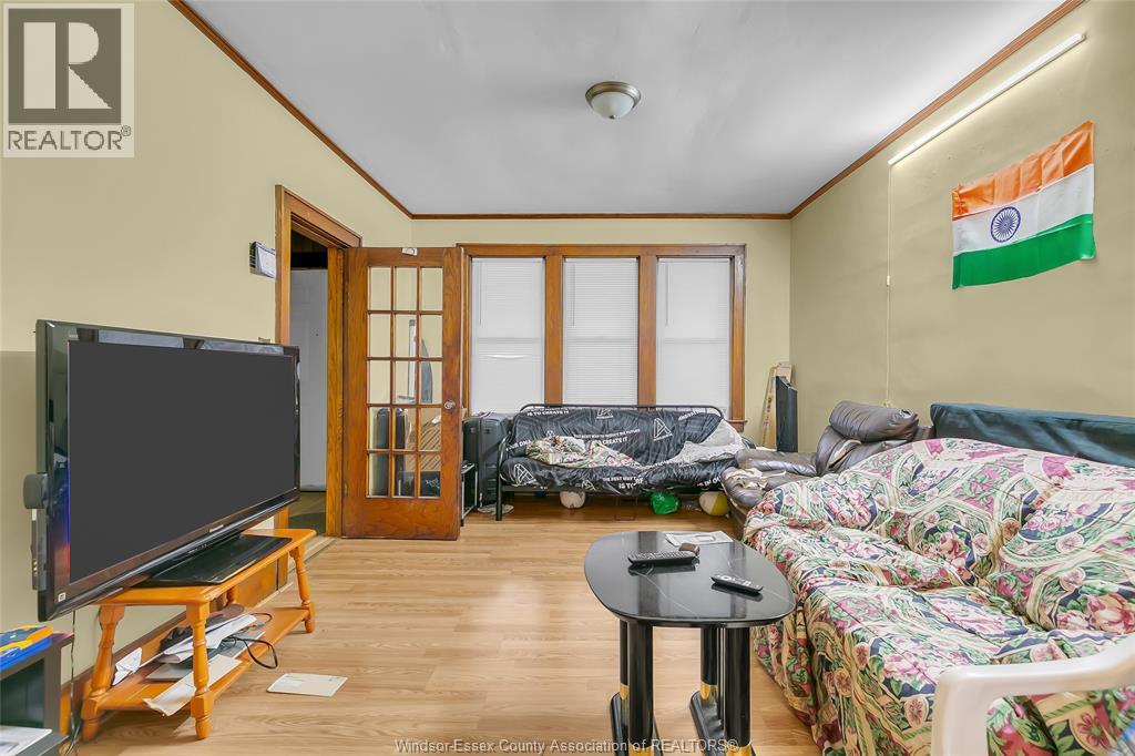 A living room with a television, sofa, and a flag of India on the wall.