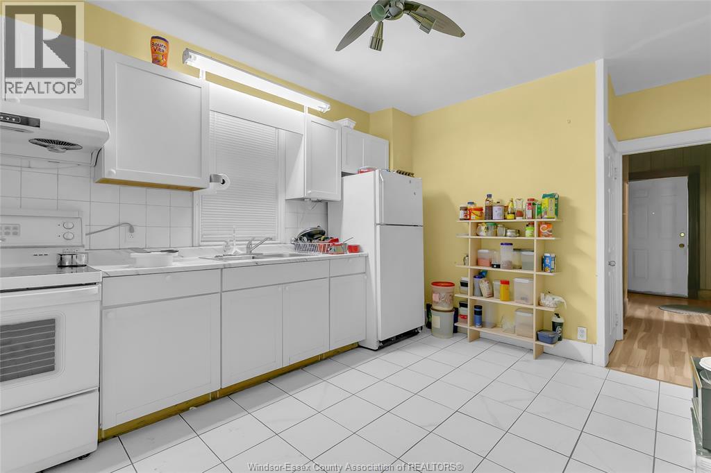 A kitchen with white cabinets and a yellow wall.
