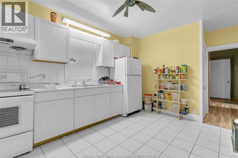 A kitchen with white cabinets and a yellow wall.