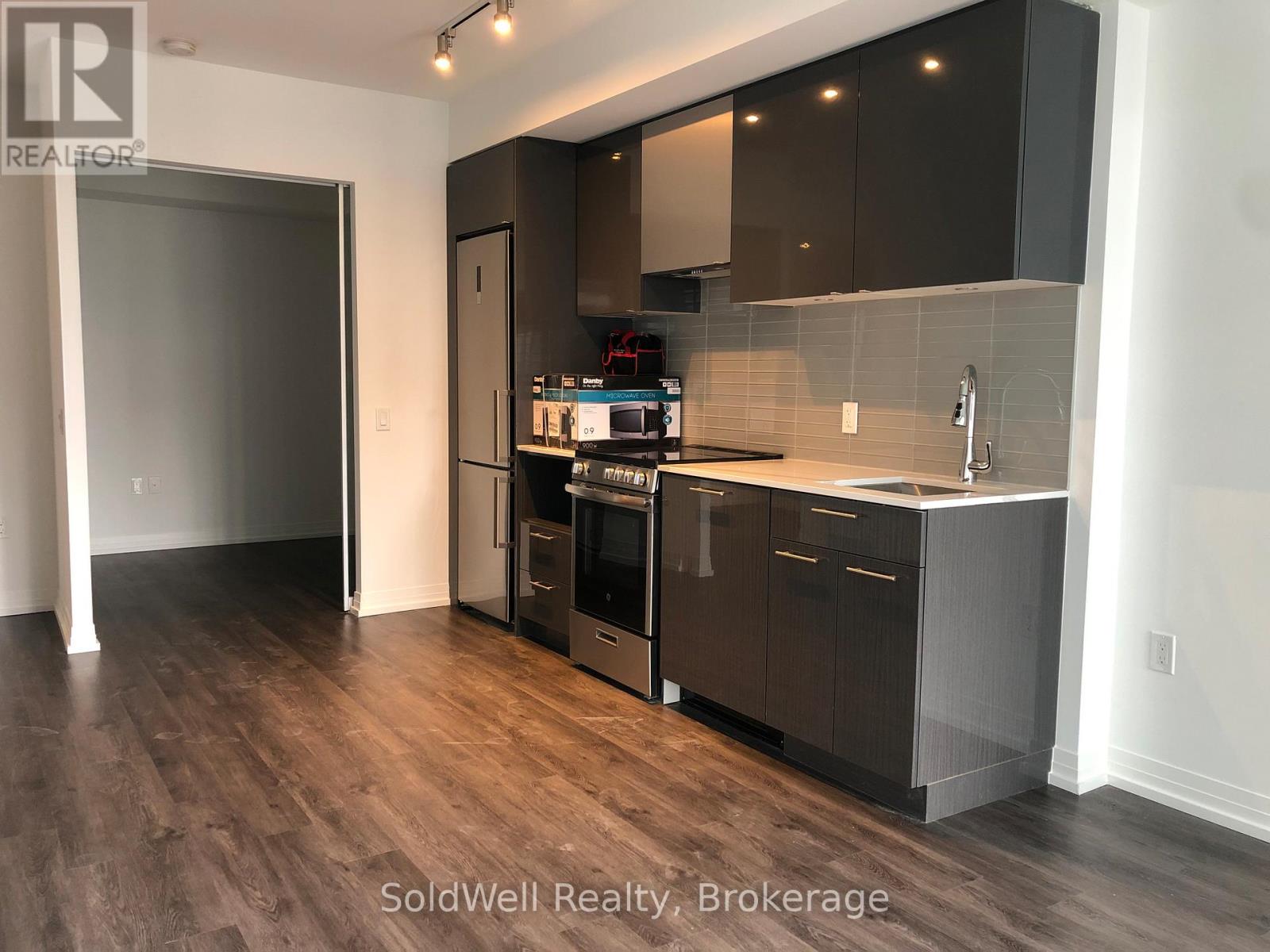 A kitchen with dark wood floors and modern appliances.