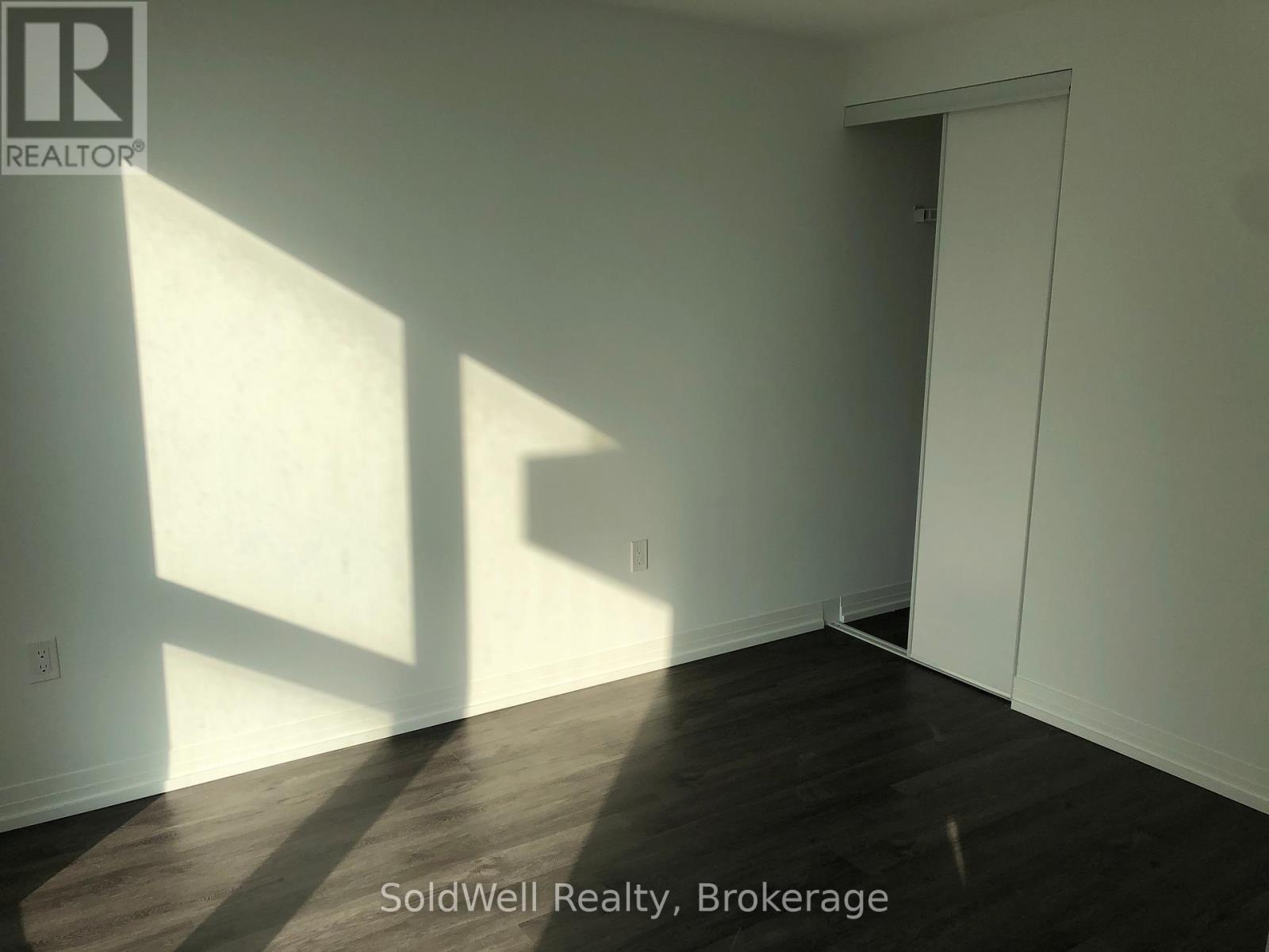 A room with wooden flooring and white walls, with sunlight shining through a window.