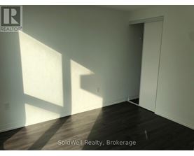 A room with wooden flooring and white walls, with sunlight shining through a window.