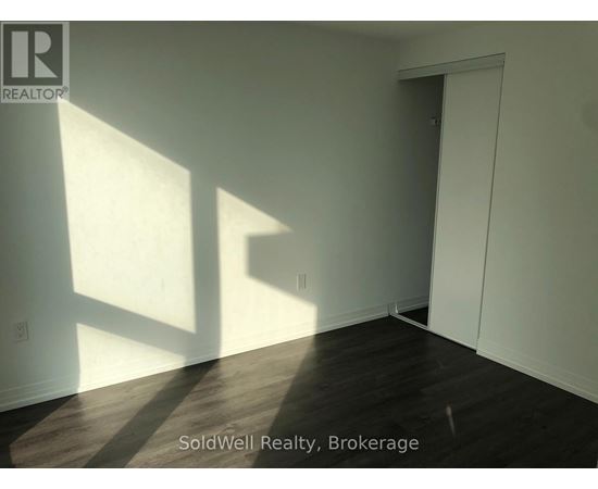 A room with wooden flooring and white walls, with sunlight shining through a window.