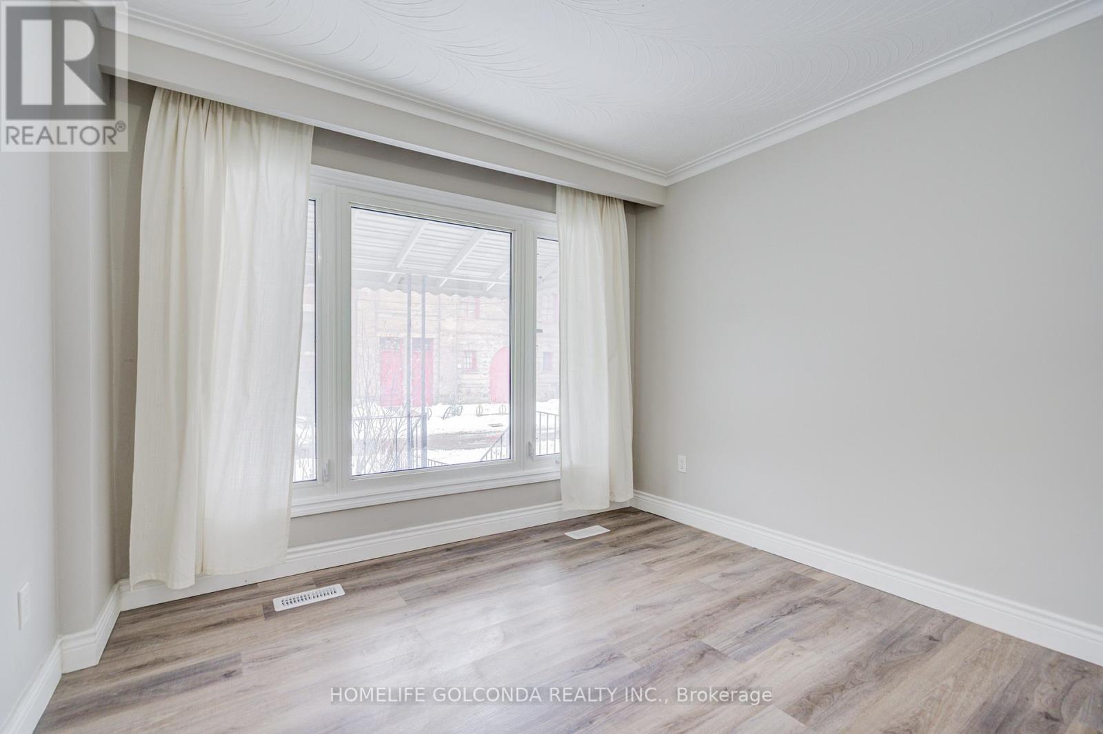 A room with a large window and wooden flooring.
