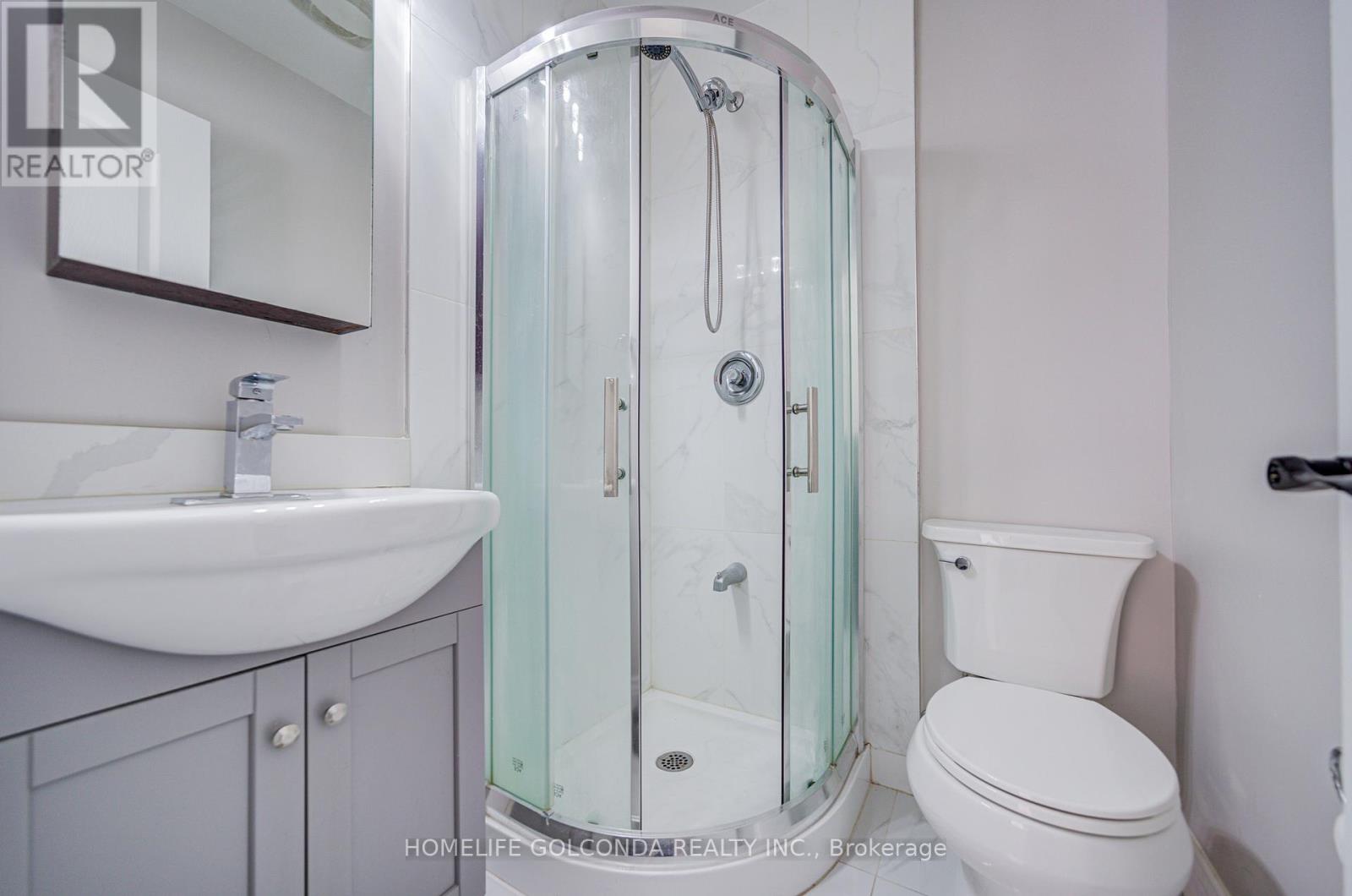 A white toilet sits next to a glass shower stall in a bathroom.