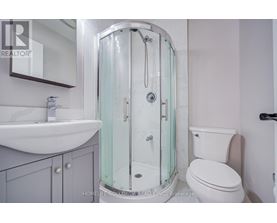 A white toilet sits next to a glass shower stall in a bathroom.