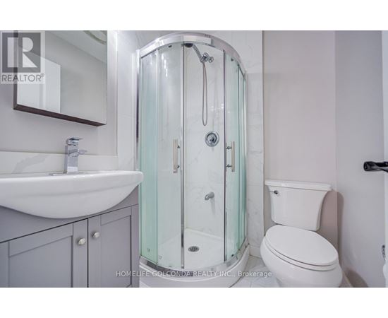 A white toilet sits next to a glass shower stall in a bathroom.