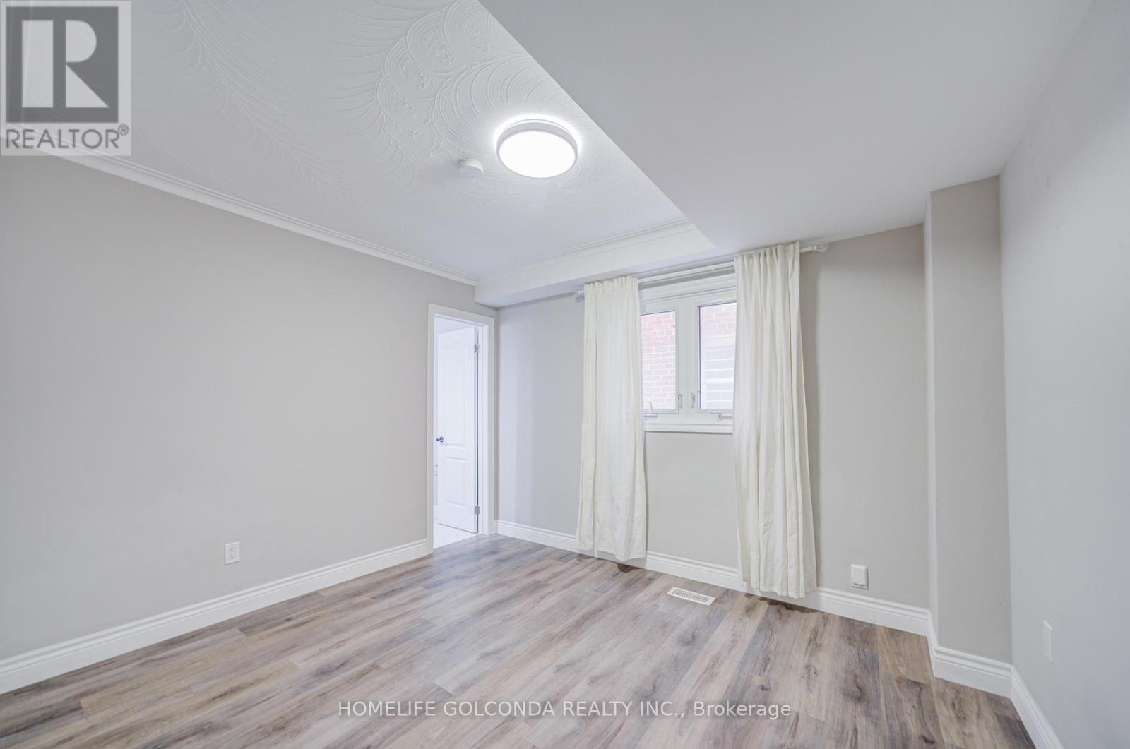 A room with a door and a window with white curtains.
