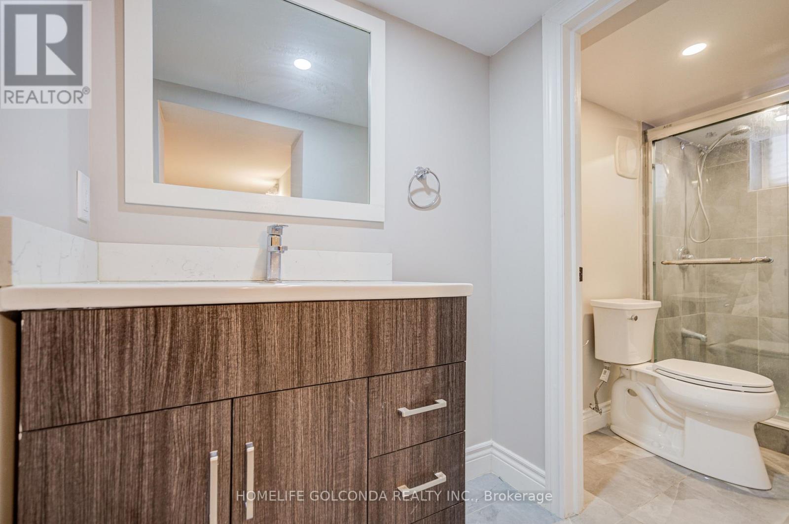 A bathroom with a white toilet and a wooden cabinet.