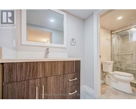 A bathroom with a white toilet and a wooden cabinet.