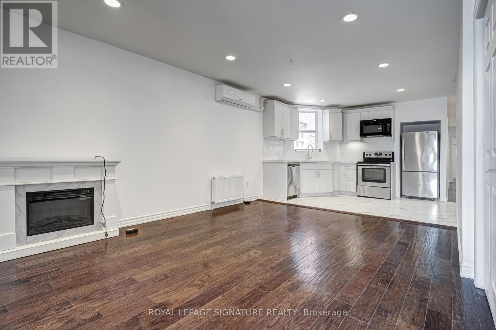 A spacious living room with wood flooring and a fireplace.