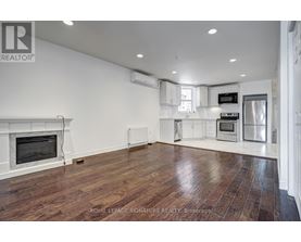 A spacious living room with wood flooring and a fireplace.