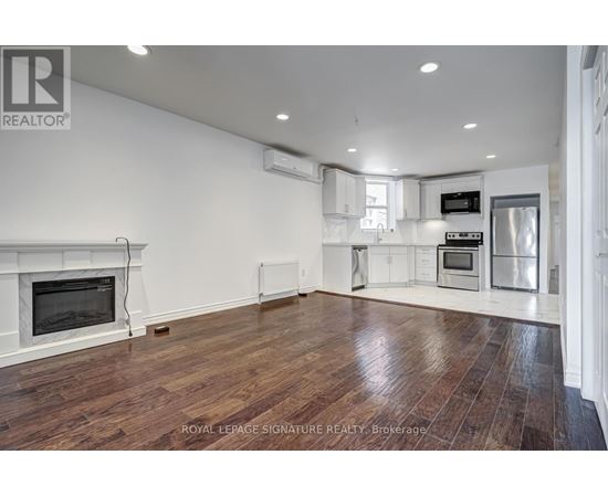 A spacious living room with wood flooring and a fireplace.