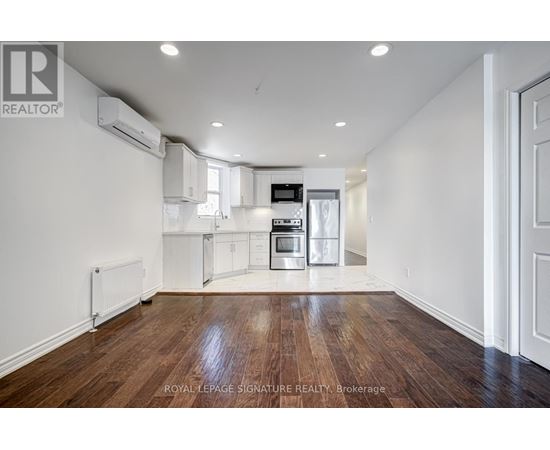 A spacious kitchen with white cabinets and a wooden floor.