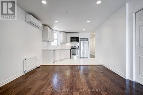 A spacious kitchen with white cabinets and a wooden floor.