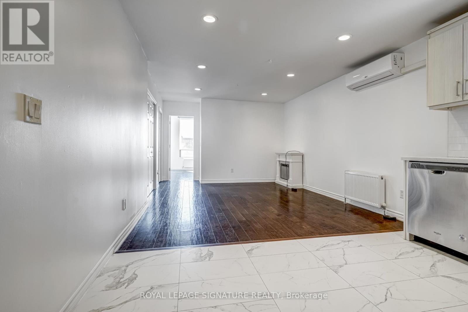 A spacious room with a wooden floor and white walls.