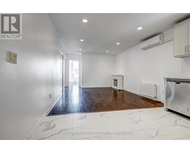 A spacious room with a wooden floor and white walls.
