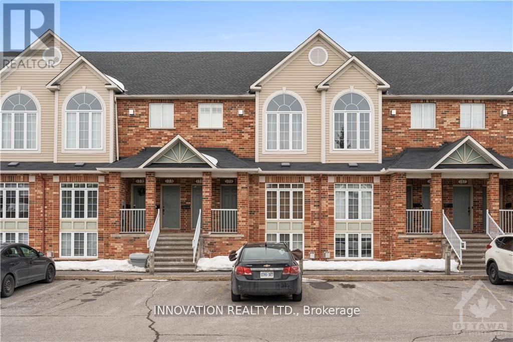 A car is parked in front of a brick building with a sign that reads "Innovation Realty LTD, Brokerage".