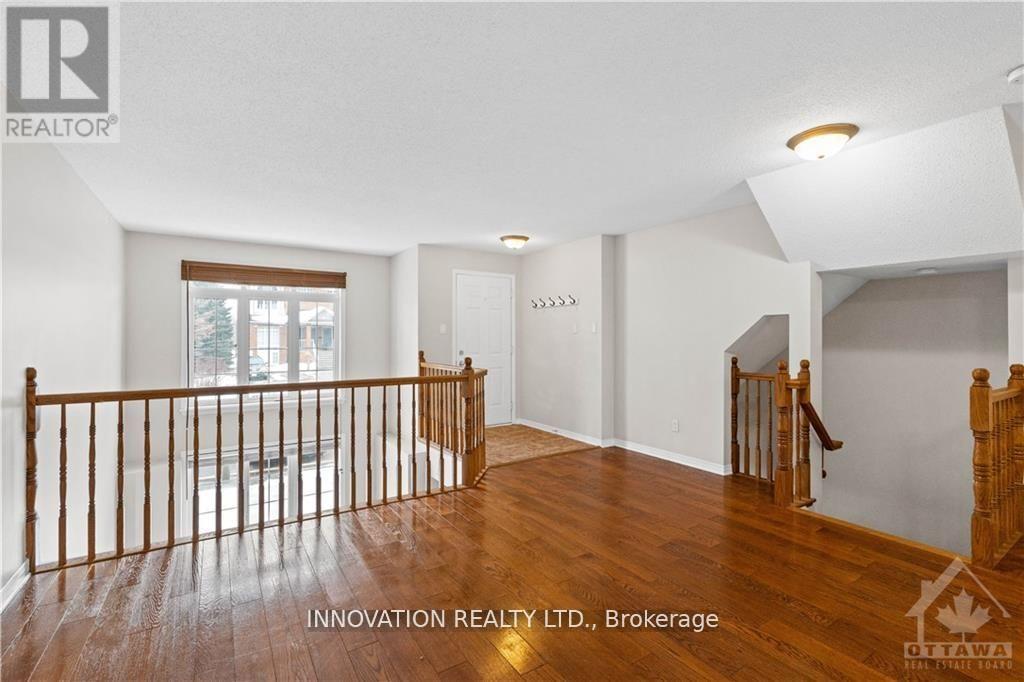 A spacious room with wooden floors and white walls, featuring a staircase with a wooden banister.
