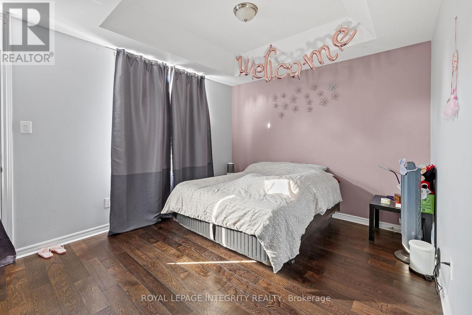 A bedroom with a bed, nightstand, and a wall with a "Welcome" sign.