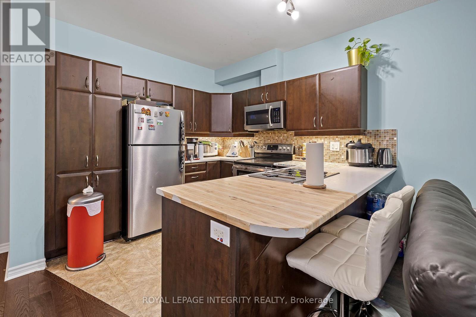 A kitchen with a refrigerator, microwave, oven, and sink.