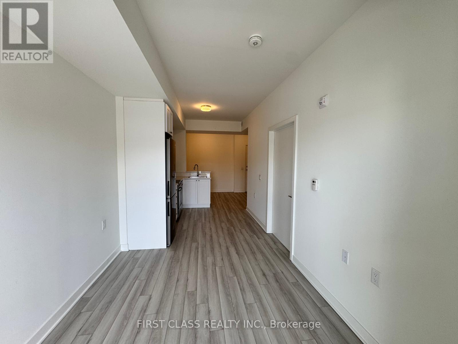 A long hallway with wood flooring and white walls.
