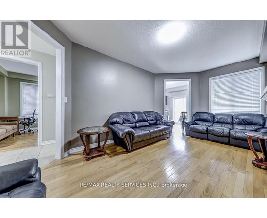 A living room with a black leather couch and a wooden floor.