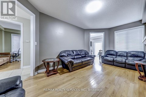 A living room with a black leather couch and a wooden floor.