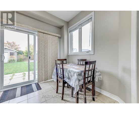 A dining room with a table set for two and a view of a backyard.