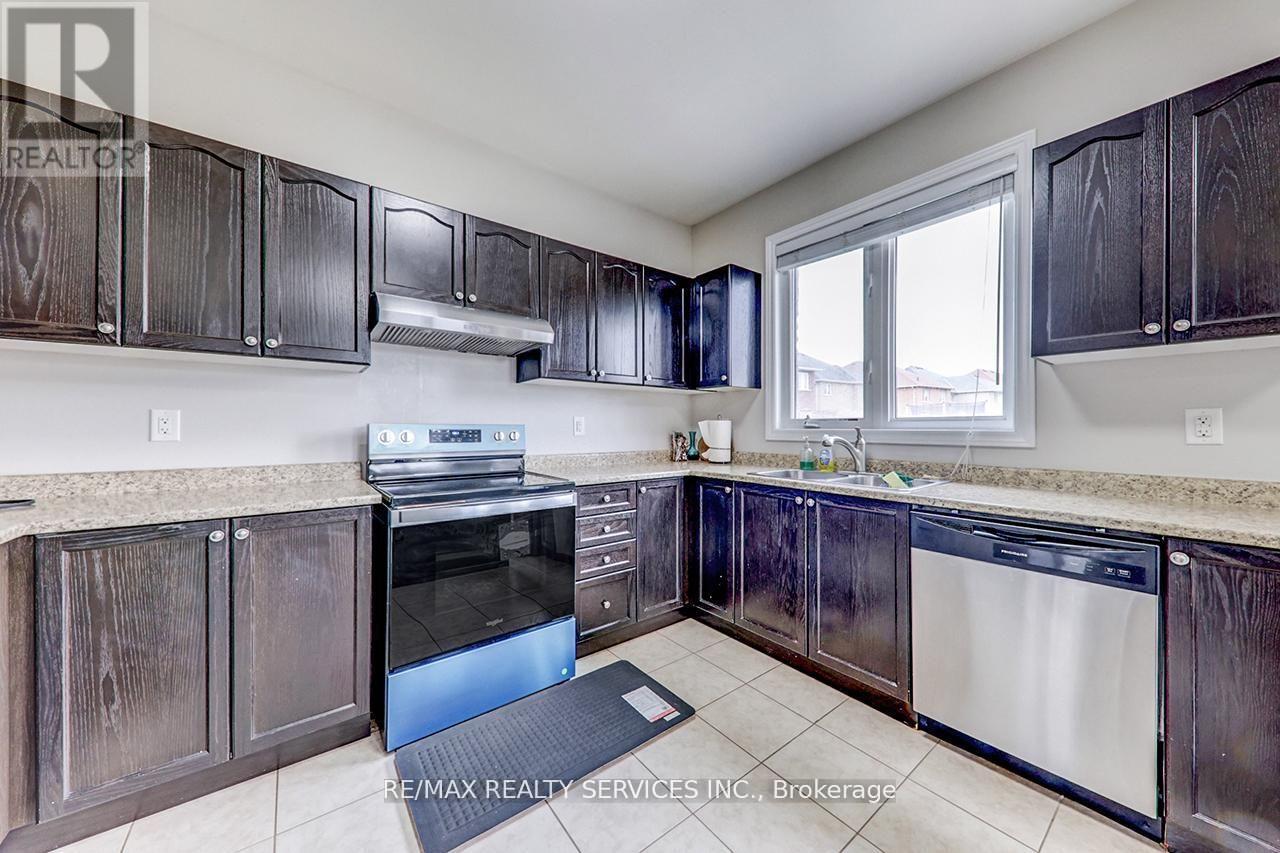 A kitchen with dark wood cabinets and a stainless steel dishwasher.