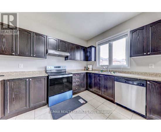 A kitchen with dark wood cabinets and a stainless steel dishwasher.