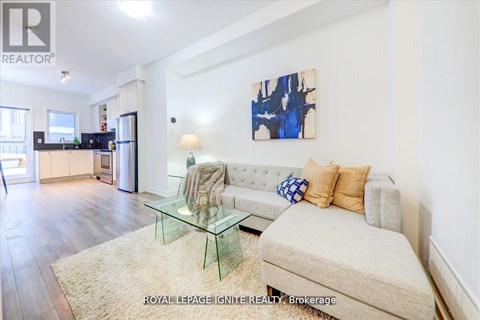 A living room with a couch, a glass table, and a painting on the wall.