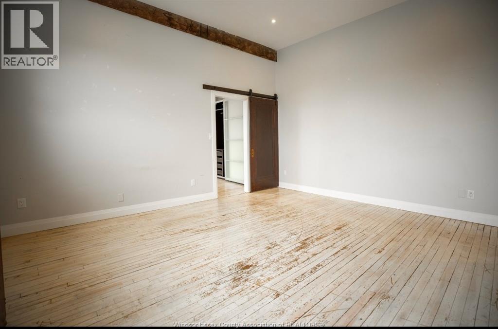 A room with wooden flooring and a doorway leading to another room.