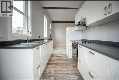 A kitchen with white cabinets and a wooden floor.