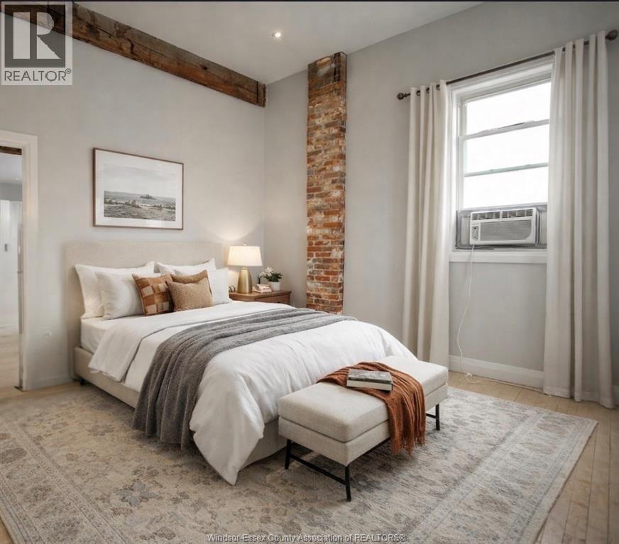 A bedroom with a large bed and a brick pillar.