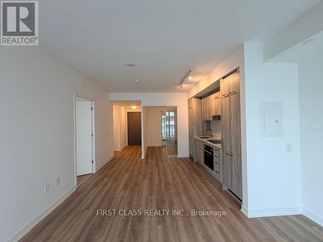A spacious room with wooden flooring and white walls.