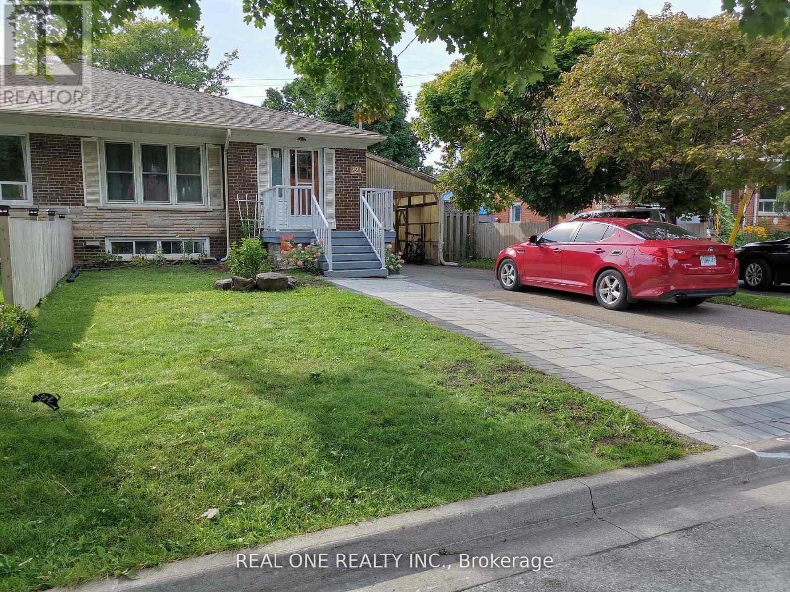 A red car is parked on the street in front of a house.