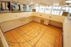 A basketball court inside a gym with wooden flooring and white walls.