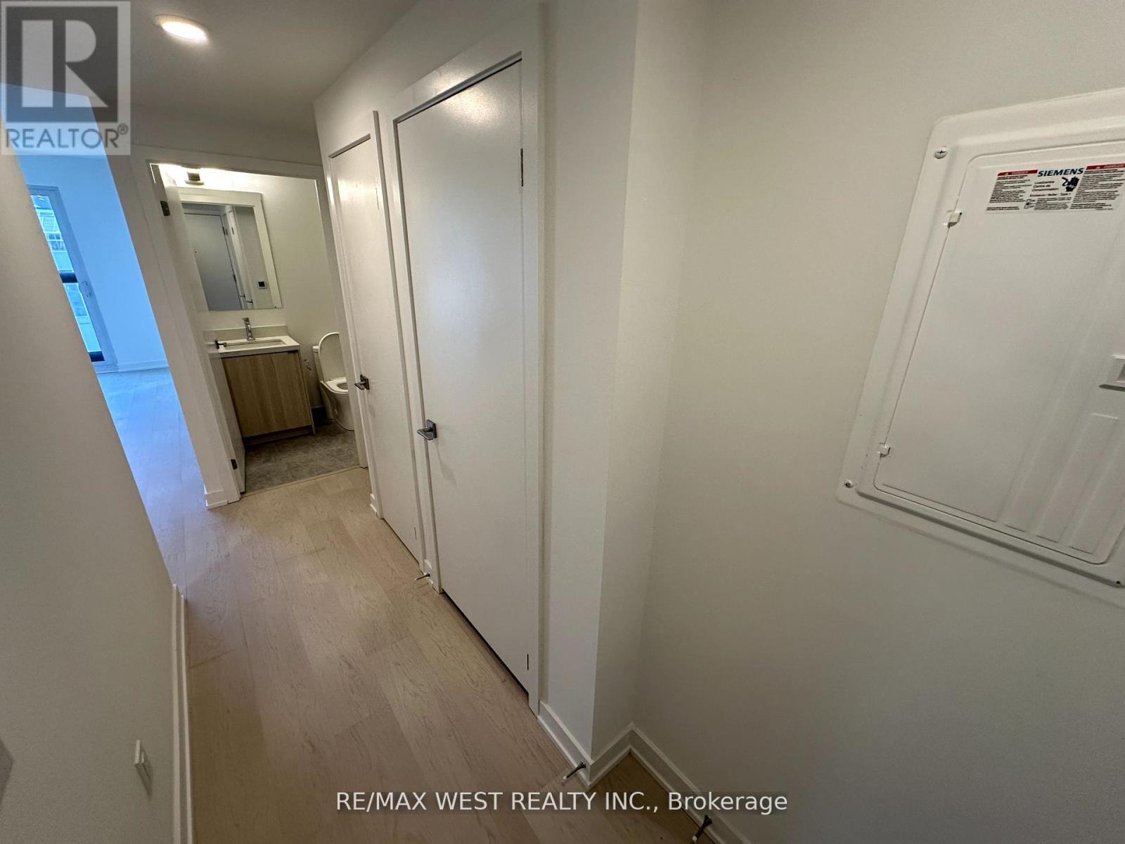 A hallway with a door on the right and a mirror on the left.