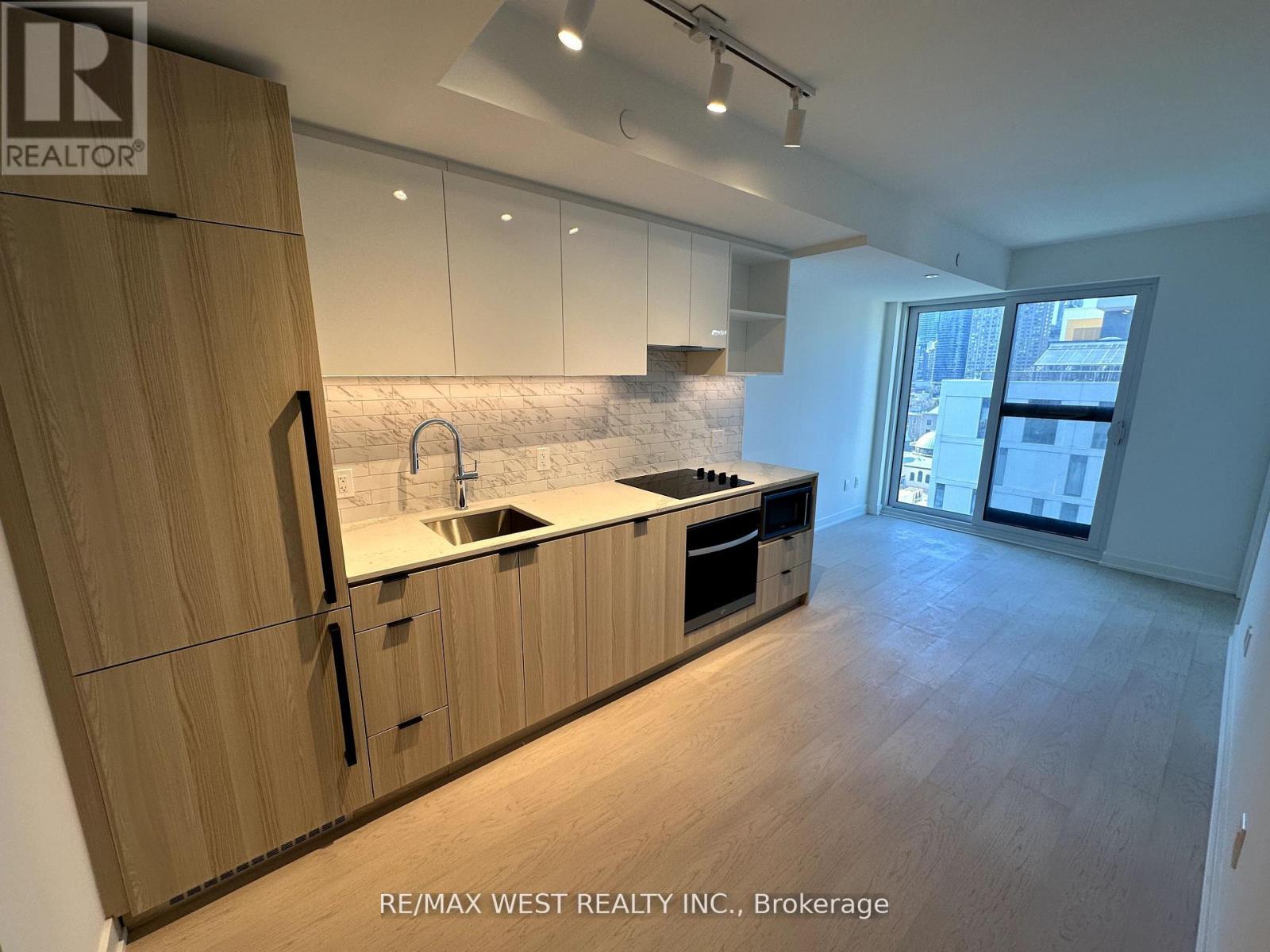 A modern kitchen with wooden cabinets and a marble backsplash.