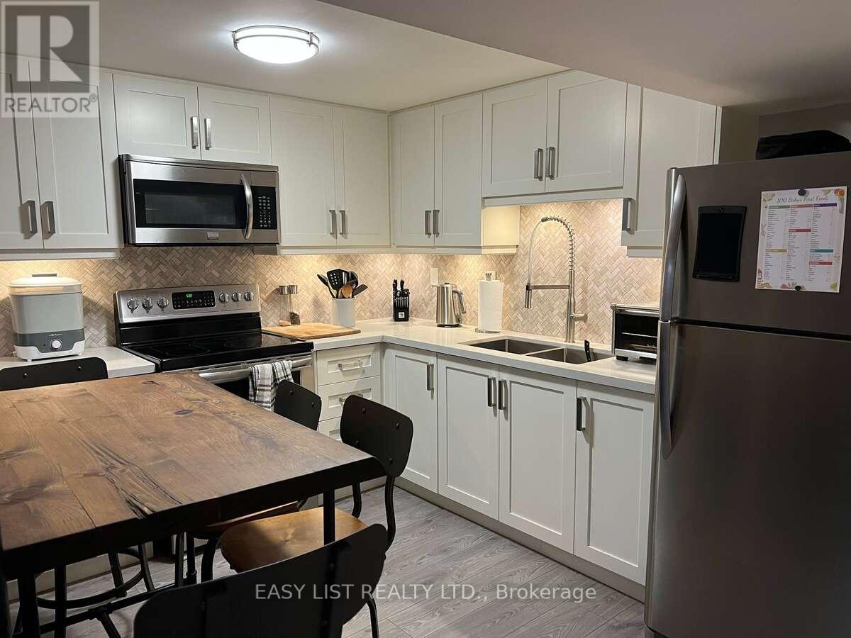 A kitchen with a wooden table and chairs, a microwave, oven, sink, and refrigerator.
